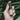 A hand holds Annmarie Probiotic Serum, a bio facial elixir, against a green, leafy background.
