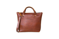 Showcases a stylish brown leather tote bag with shoulder strap and front pocket, against a white background.
