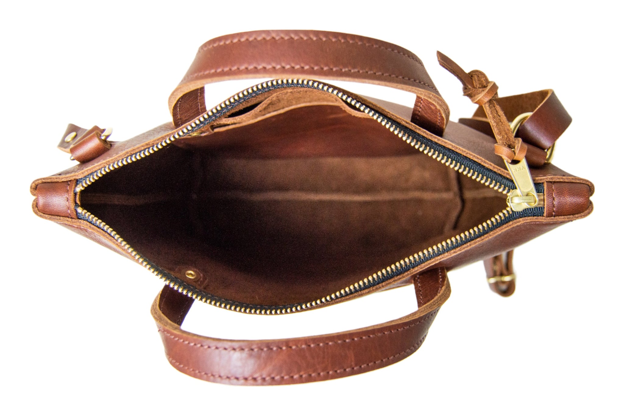 A view from above showcases the open, spacious interior of a brown leather tote bag with a zipper closure and carrying handles.
