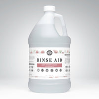 A gallon jug displays Rustic Strength Rinse Aid, highlighting its light cherry aroma and essential oil formula.
