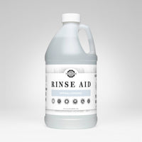 A bottle of Rustic Strength Rinse Aid displays its hypoallergenic and biodegradable formula, promising spotless, sparkling dishes with a short dry time.
