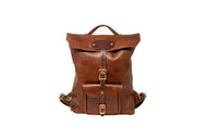 A vintage-style leather backpack with brass buckles sits against a white backdrop.
