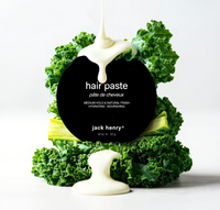 Creamy Jack Henry hair paste drips onto kale arranged around the product label.
