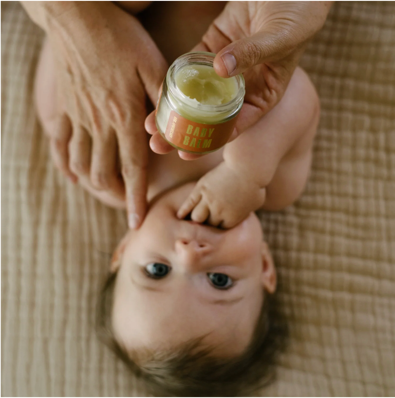 Woman applying baby balm to a baby.
