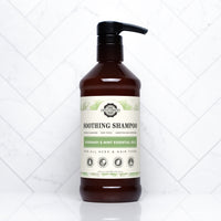 A bottle of Rustic Strength Soothing Shampoo with rosemary and mint essential oils sits against a white tile background.