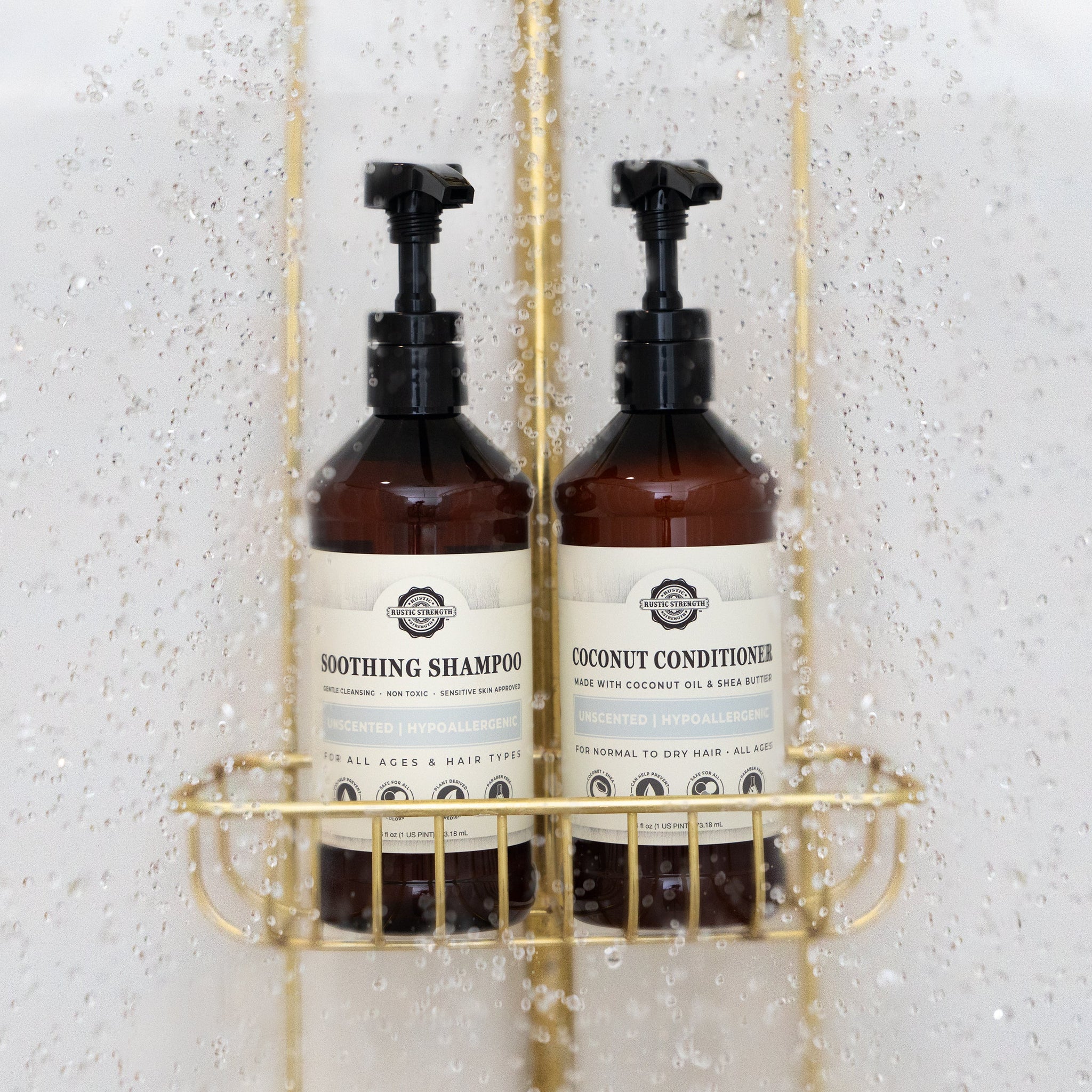 Shower water streams over Rustic Strength's unscented, hypoallergenic soothing shampoo and coconut conditioner set for all hair types, displayed in a gold shower caddy.
