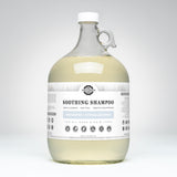 Rustic Strength Soothing Shampoo, a hypoallergenic and unscented haircare product for all ages, sits in a clear glass jug with a white cap.
