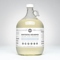 Rustic Strength Soothing Shampoo, a hypoallergenic and unscented haircare product for all ages, sits in a clear glass jug with a white cap.
