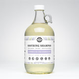 Rustic Strength soothing shampoo infused with lavender and tea tree essential oils sits in a clear glass bottle with a handle.
