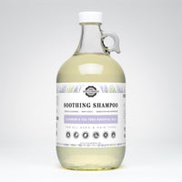 Rustic Strength soothing shampoo infused with lavender and tea tree essential oils sits in a clear glass bottle with a handle.
