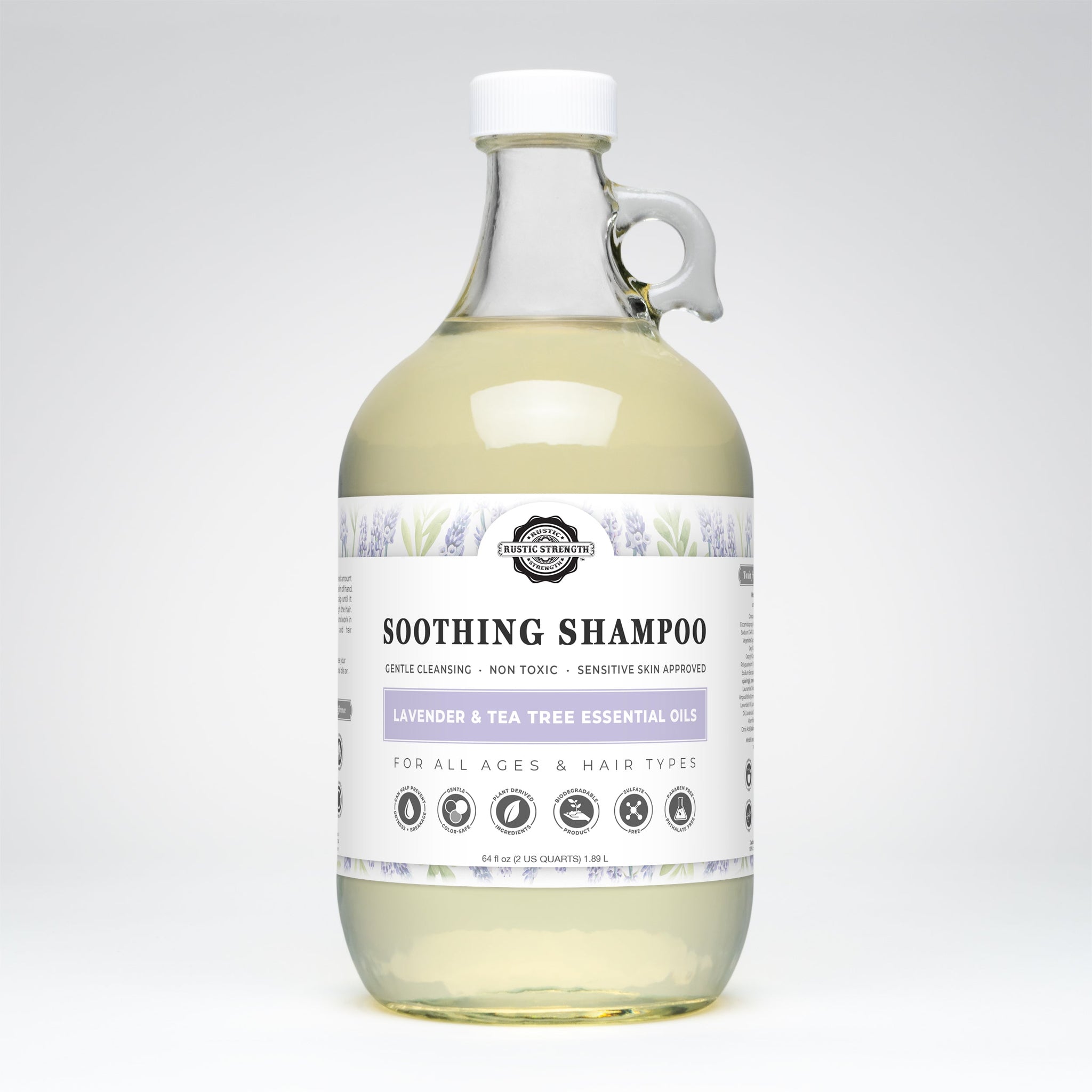 Rustic Strength soothing shampoo infused with lavender and tea tree essential oils sits in a clear glass bottle with a handle.
