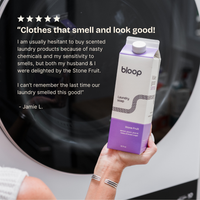 A woman holds a carton of Bloop Stone Fruit laundry soap in front of a washing machine, highlighting its pleasant scent and cleaning power based on a customer review.
