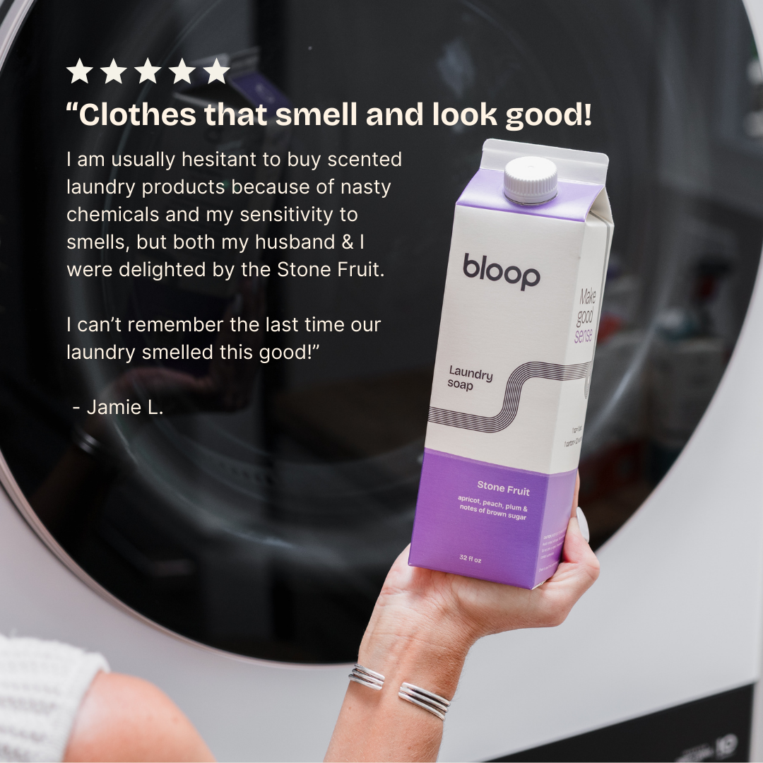 A woman holds a carton of Bloop Stone Fruit laundry soap in front of a washing machine, highlighting its pleasant scent and cleaning power based on a customer review.
