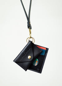 A black leather lanyard wallet with a Discover card hangs against a white background.
