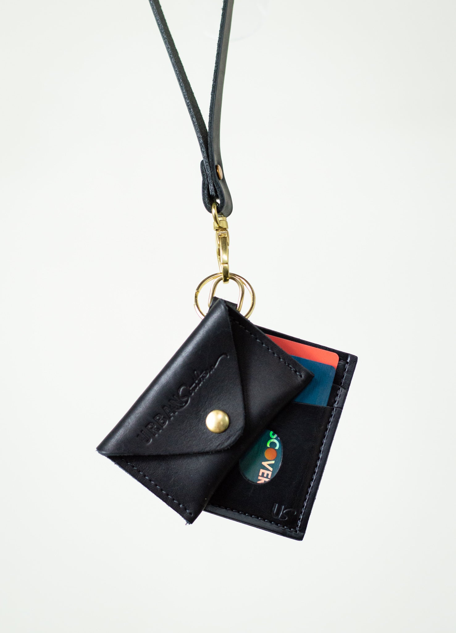 A black leather lanyard wallet with a Discover card hangs against a white background.
