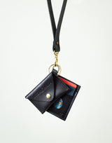 A black leather lanyard wallet holding credit cards hangs against a white background, showcasing convenient cardholder style.
