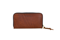 Urban Southern displays their brown leather zip-around wallet with a tassel pull.
