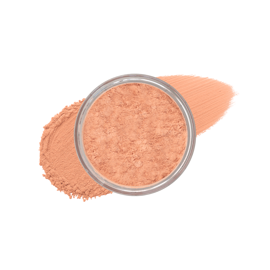 Loose peach powder foundation sits in a clear container next to a swatch of the same makeup.
