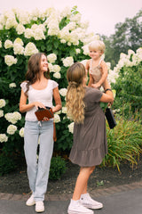 Two young women and a toddler boy enjoy a day outdoors among blooming hydrangea bushes.
