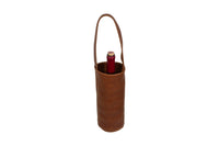 A red wine bottle sits inside a brown leather wine tote with a handle.
