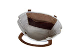 The canvas tote bag features brown leather handles and a convenient internal leather pocket.
