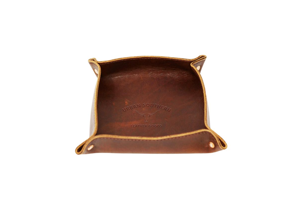 Showcases an Urban Southern leather valet tray with its logo stamped inside.
