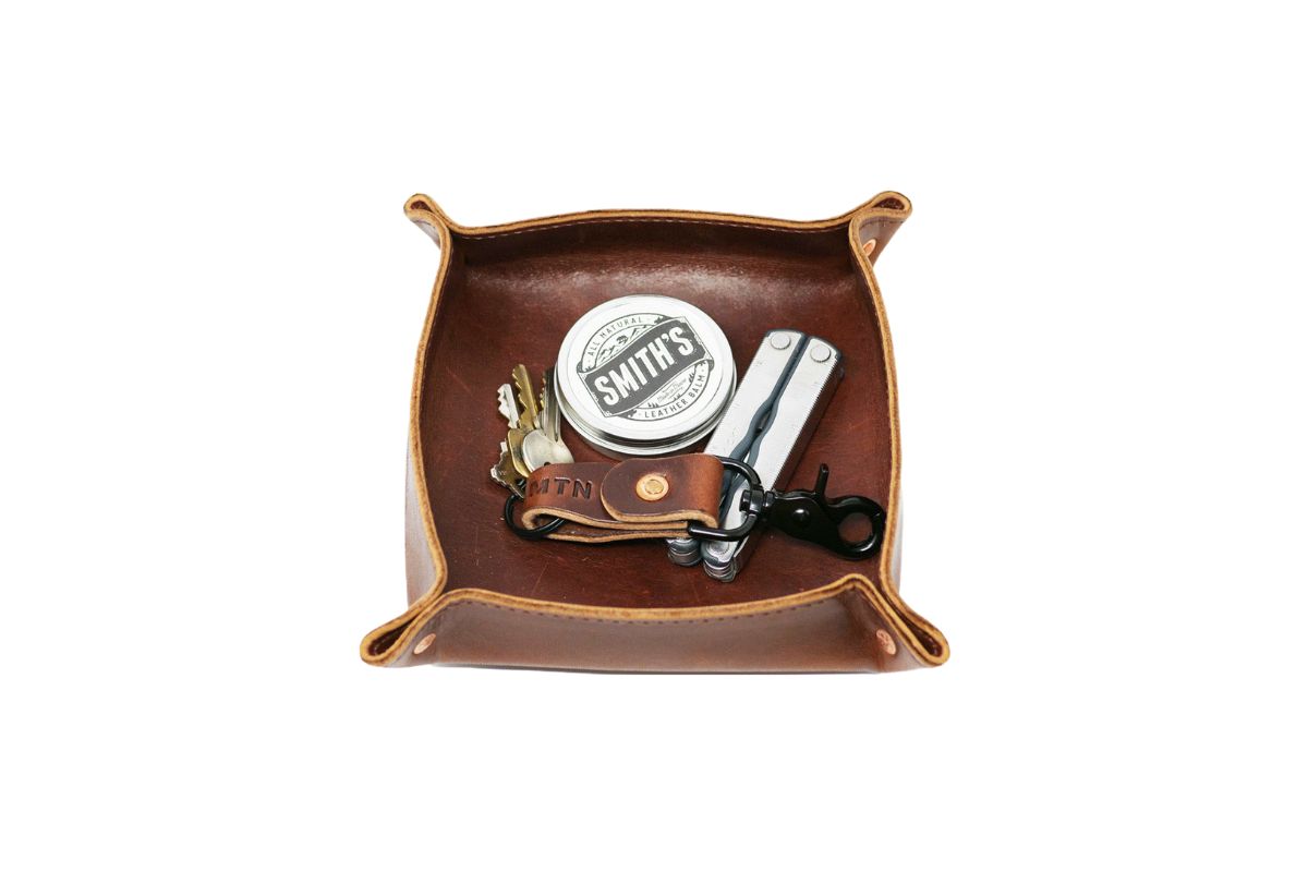 A leather valet tray holds keys, a multi-tool, and Smith's Leather Balm.
