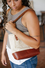 A woman models the Urban Southern leather and canvas tote bag over her shoulder.
