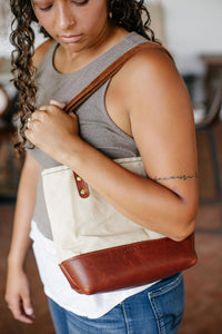 A woman models the Urban Southern leather and canvas tote bag over her shoulder.
