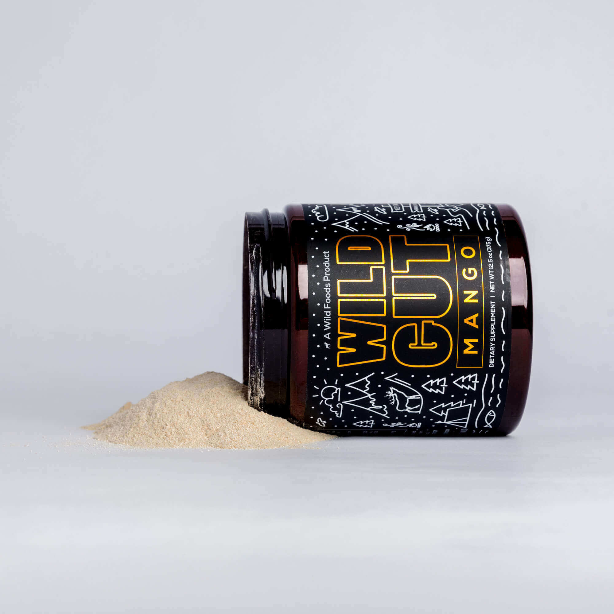 An opened jar of Wild Gut Mango dietary supplement spills its powder onto a white surface.

