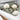 Three wool dryer balls tumble with olive-green fabric inside a white laundry dryer.
