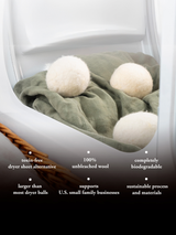 Inside a dryer, wool dryer balls sit atop a folded green linen sheet, offering an eco-friendly and sustainable laundry solution.
