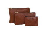 Three "Urban Southern" brown leather zipper pouches present a stylish, tiered organizational solution.
