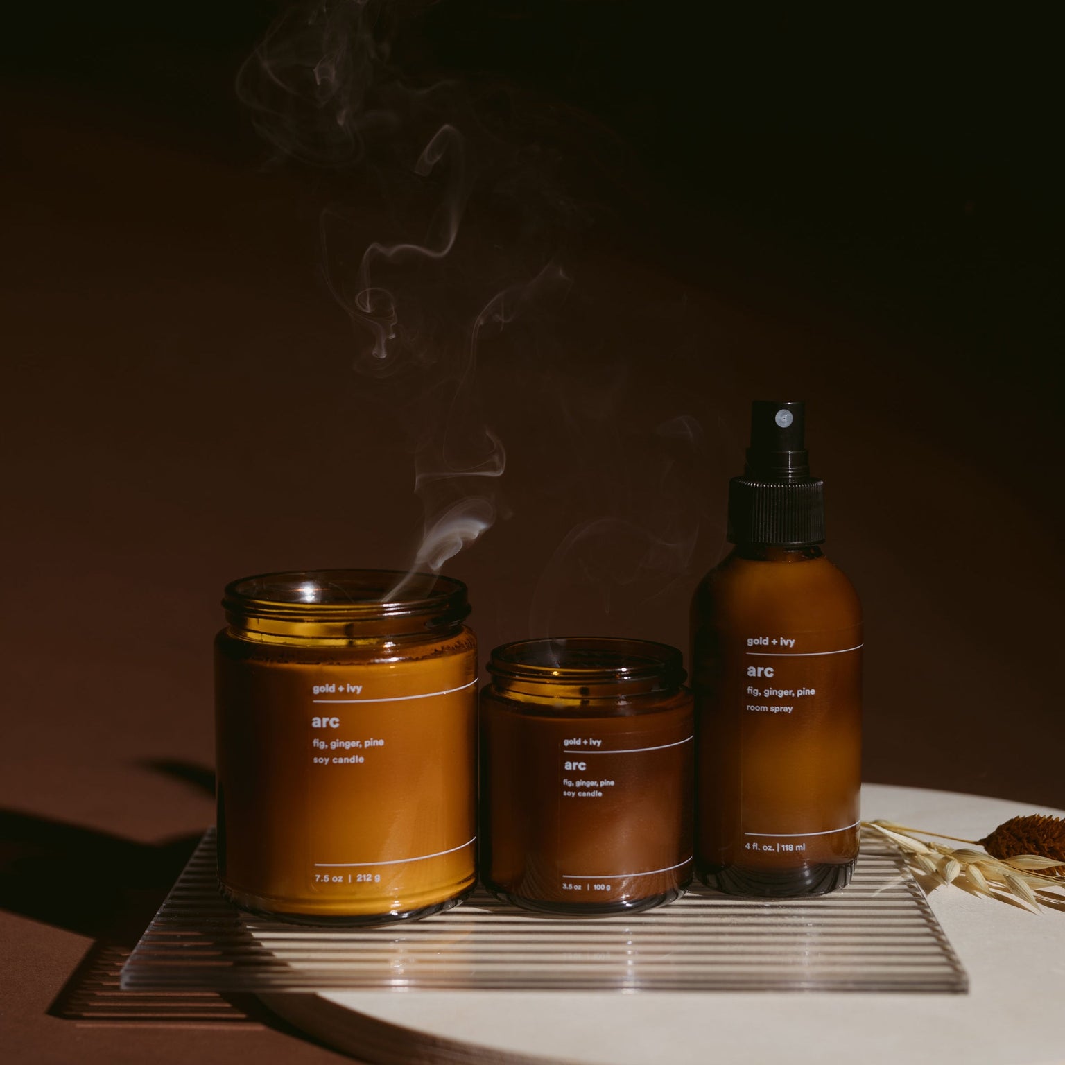 Three amber-colored jars and a spray bottle on a dark background with smoke rising.
