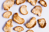Arranged Lion's Mane mushroom slices display their unique texture on a white surface.
