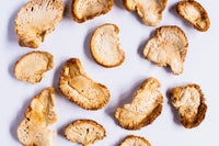 Arranged Lion's Mane mushroom slices display their unique texture on a white surface.

