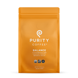 Showcases a sealed orange bag of Purity Coffee Balance, a consciously crafted, two-thirds decaffeinated, USDA-organic ground coffee for metabolic health.
