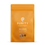 Purity Coffee displays its Balance blend of two-thirds decaffeinated, USDA Organic, Bird Friendly whole bean coffee in a bright orange bag.
