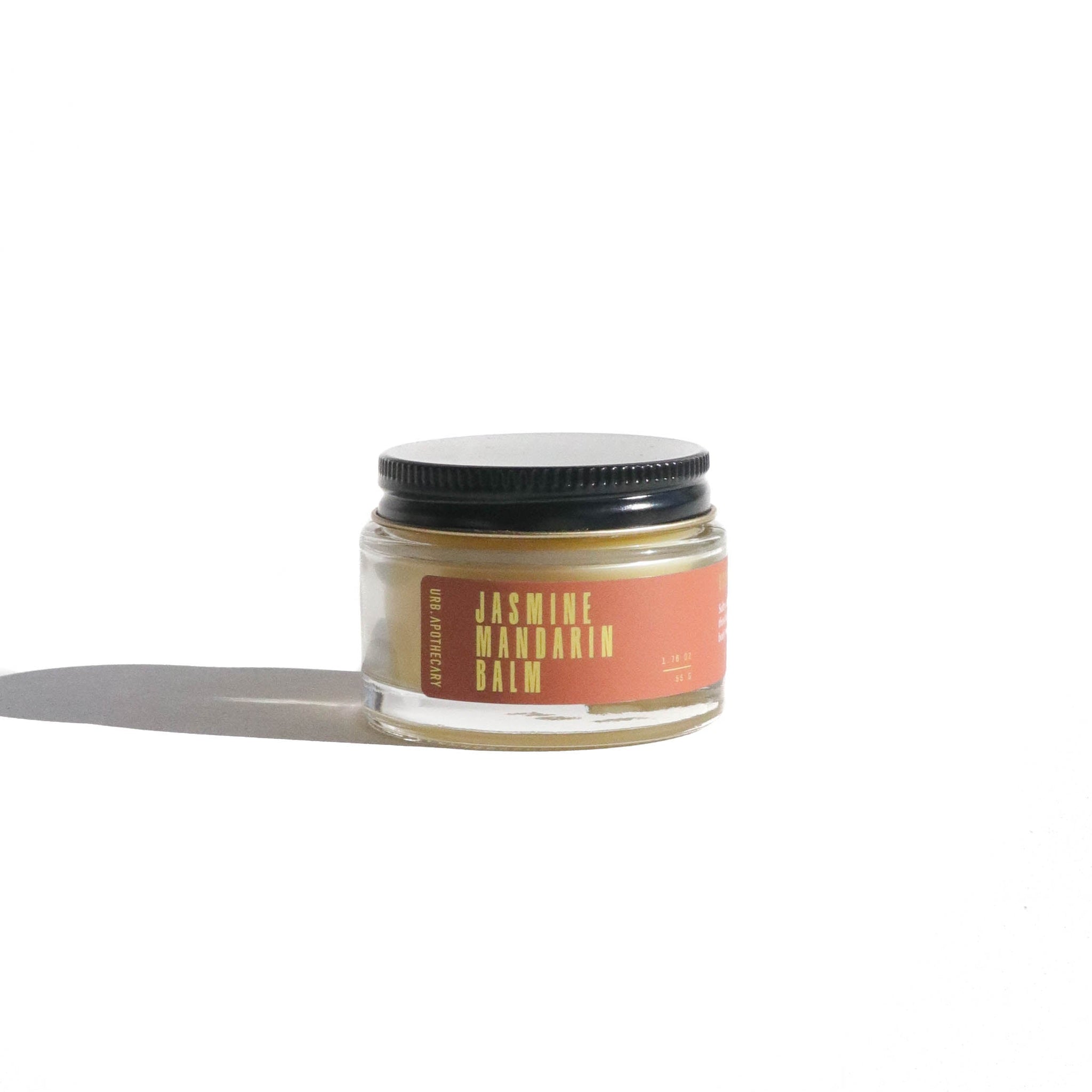Shows a jar of URB Apothecary Jasmine Mandarin Balm with a black lid on a white background.
