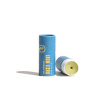 Two tubes of URB Apothecary Basil Mint Lip Balm sit on a white surface, one open to show the balm.
