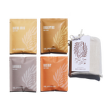 Urb Apothecary displays a curated set of bath soaks, including cactus milk, eucalyptus, lavender, and rosehip, packaged in individual sachets and a cloth gift bag.

