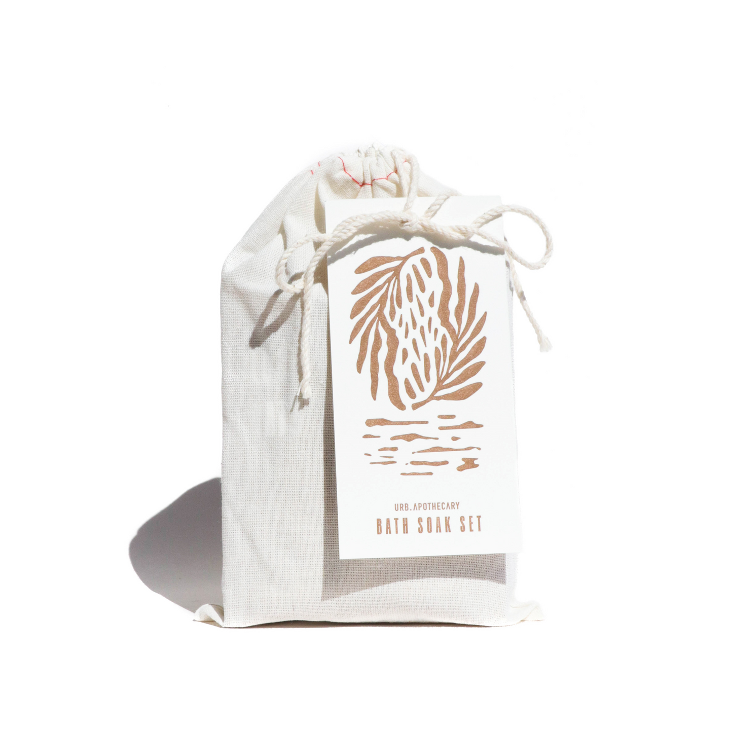 Showcases a URB Apothecary bath soak set packaged in a charming white drawstring bag, accentuated by a decorative botanical tag.
