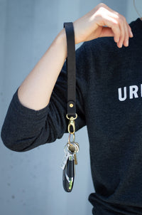 Person displays a black leather Urban Southern wristlet keychain with keys.
