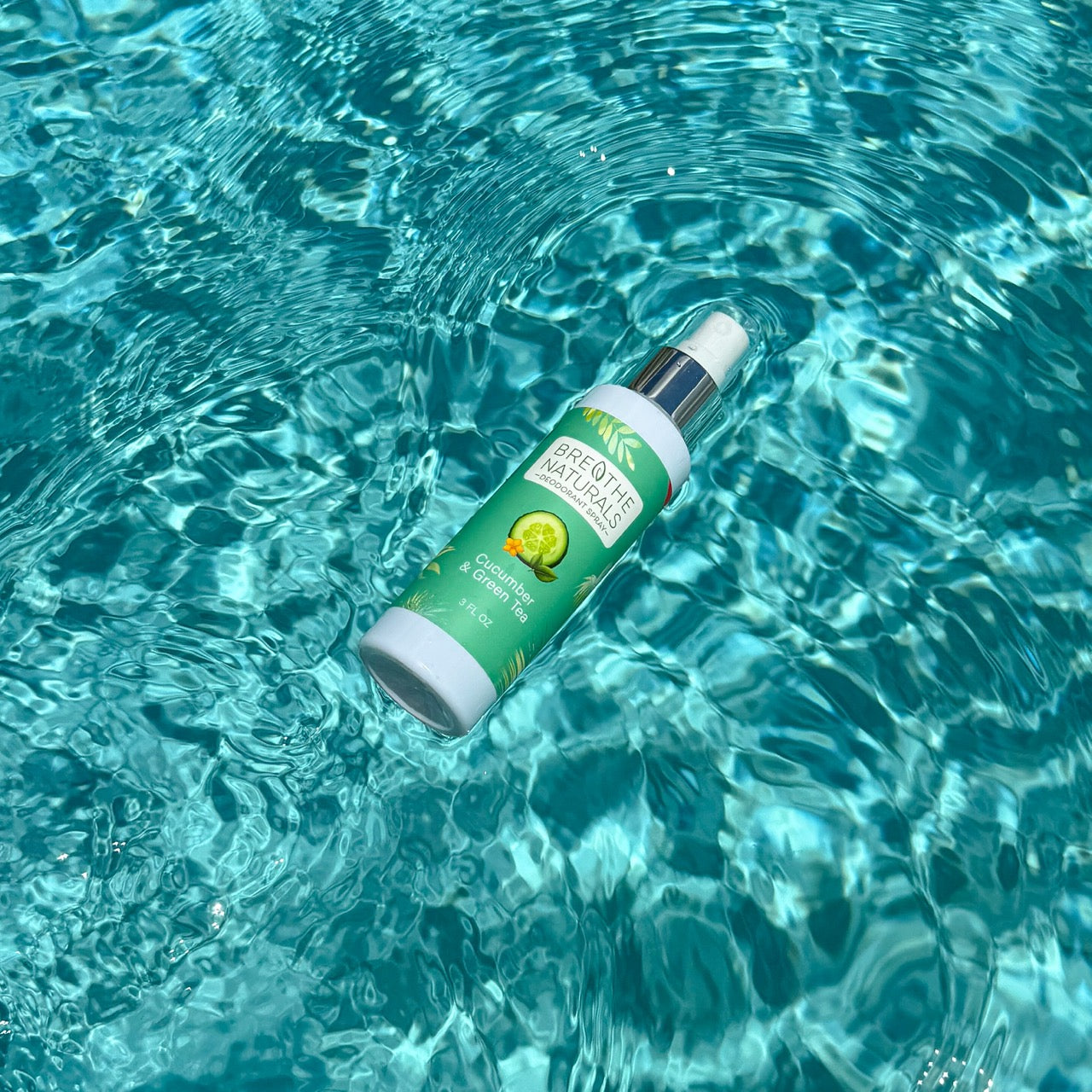 Breathe Naturals cucumber and green tea deodorant spray floats in shimmering turquoise water.
