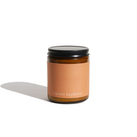Cypress bayberry candle sits on a white surface, casting a shadow.
