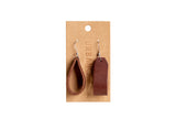 Displays Urban Southern leather earrings, one teardrop and one rectangular, hanging on a branded kraft paper card.
