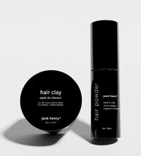 Displays Jack Henry hair clay and hair powder products, showcasing their minimalist black packaging.
