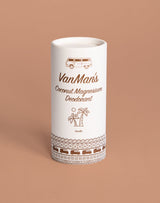 A white tube of VanMan's Coconut Magnesium Vanilla Deodorant displays camper van and palm tree illustrations against a tan background.
