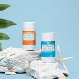 Breathe Naturals displays their Orange Creamsicle and Cooling Cocomint deodorants on white rocks with starfish against a light blue background.
