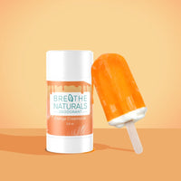 Breathe Naturals orange creamsicle deodorant poses next to a matching orange creamsicle popsicle.
